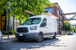 © vit - Commercial cargo mini van with ladder on the roof standing on the urban city street with apartment buildings