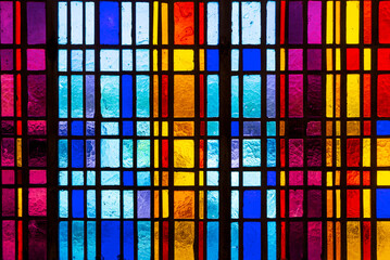 Colorful stained glass window in modern design with blue, red, violet and yellow pieces of glass