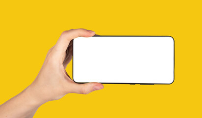 Aufkleber - Hand holding phone mockup in horizontal position on yellow background. Woman using smartphone for watching video. Android template with empty screen. High quality photo