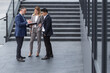© Liubomir - Colleagues company employees talking and discussing business plans outside office building, diverse business team men and women discussing financial reports and contract documents on stairs