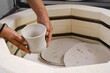 © ninelutsk - close-up of hands putting vase into the kiln, oven for roasting of unbaked clay handmade products, Unfinished ceramics and utensil. Modern pottery oven ready for firing.