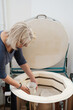 © ninelutsk - Woman artist putting ceramics into kiln. Raw pottery ready to be fired in oven. Ceramist working in studio making vases and plates. Clay modeling workshop