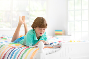 Wall Mural - Child reading in bed. Kids read. Boy at home.