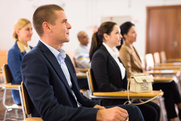 Wall Mural - Portrait of focused male attentively listening to lecture with colleagues at conference