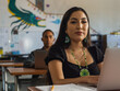 © INDÍGENA - Native girl looking into the camera while typing on her computer