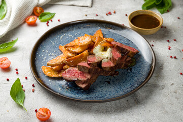 Wall Mural - Beef steak sliced with potato wedges on grey table