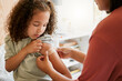 © Kay A/peopleimages.com - Covid nurse vaccinating child putting a bandage on at a clinic. Doctor applying plaster on girl after an injection at health centre. Pediatric, immunity and prevention at medical childrens hospital