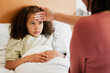© Kay A/peopleimages.com - Concerned, anxious and unwell girl suffering with cold or flu while her mother checks her temperature at home. Worried parent caring for her sick child, feeling for fever while worrying about corona