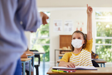 Poster - Smart student with covid face mask asking teacher question about corona virus pandemic in a classroom or elementary school. Little girl child raising hand to answer healthcare related topic in class