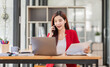 © David - Young Business Asian woman talking on a smartphone and working in an office. Asian female Business accountant Documents data sitting at his workplace.