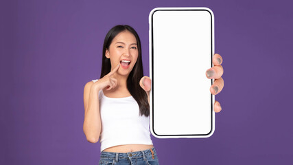 Beautiful Asian brunette woman cute girl in white tank top ,Excited surprised girl showing big smart phone with blank screen , white screen isolated purple background , Mock Up Image