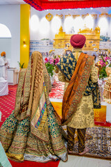 Indian Punjabi Sikh wedding at gurdwara, bride and groom back view