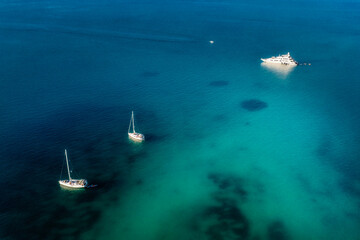 Wall Mural - Aerial drone view of sailing boats in the blue turquoise clear ocean or sea at sunset. Travel, vacation, weekend background. Peaceful seascape. Beautiful calming landscape