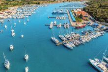 Aerial View Of Luxure Yachts And Motorboats Moored In A Port With Clear Blue Water In Summer. Top View From Drone Of Sailboats And Various Speed Boats In Dock. Pula, Croatia