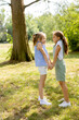 Two little girls holding hands in the park