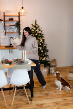 Woman With King Charles Spaniel Dog At Home Kitchen With New Year Tree.