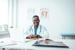 © Dragana Gordic - Portrait Of Smiling male Doctor Wearing White Coat With Stethoscope Sitting Behind Desk In Office. Happy male medical doctor portrait in hospital. Portrait of a male doctor with laptop