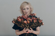 Upset elderly woman hold withered dry old rose flowers bouquet. Old age Concept.
