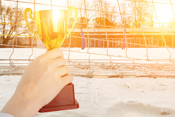 Wall Mural - sport cup, volleybal trophy,the hand of the championship winner holds the award against the background of the volleyball court