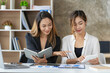 © ArLawKa - Two Asian business women working on a financial graph and a laptop.in the presentation and review of the business plan Joint financial marketing strategies in the meeting room with new employees in t