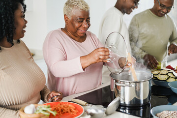 Wall Mural - Happy black family cooking vegan food inside kitchen at home - Focus on mother face