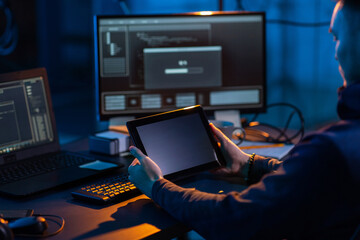 Poster - cybercrime, hacking and technology concept - close up of male hacker in dark room with tablet pc usi
