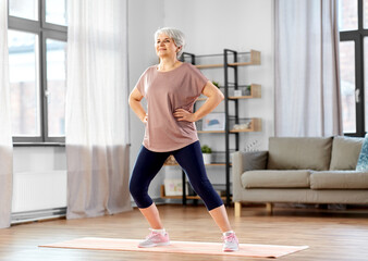 Poster - sport, fitness and healthy lifestyle concept - smiling senior woman exercising on mat at home