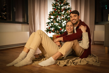 Wall Mural - holidays, celebration and people concept - happy couple hugging at home on christmas