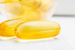 Omega-3 yellow capsules at white wooden planks, nutritional supplements, close-up view
