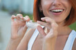 © Михаил Решетников - Red-haired Caucasian woman holding transparent mouthguards for bite correction outdoors. A girl with a beautiful snow-white smile uses silicone braces