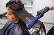 Hairdresser using a hair straightened to straighten the hair. Hair stylist working on a woman's hair style at salon.
