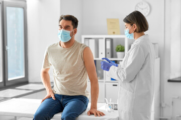 Sticker - health, medicine and pandemic concept - female doctor or nurse in protective medical mask and gloves disinfecting male patient's skin at hospital