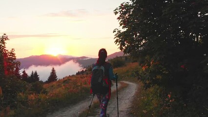 Wall Mural - Lonely happy woman portrait watch sunrise. Carefree tourist woman looking at sun enjoying landscape. Girl traveler on top of mountain in rays of sunset. Hiker is enjoying nature