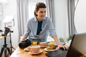 Poster - blogging, photographing and people concept - happy smiling female food blogger or photographer with laptop and camera in kitchen at home