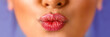 © Paulista - Close up of female mouth sending a kiss on purple blue background.