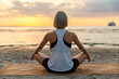 Leinwandbild Motiv yoga, mindfulness and meditation concept - woman meditating in lotus pose on beach over sunset