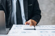 © kamiphotos - Businessman is using a calculator to calculate company financial figures from earnings papers, a businessman sitting in his office where the company financial chart is placed. Banner with copy space.