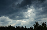 Fototapeta Tęcza - Dark blue clouds over forest