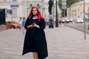 Wall Mural - European plus size woman walking outdoor street city with mobile cellular phone. Young red pink haired body positive girl using cellphone smartphone