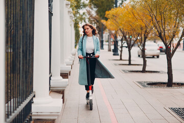 Wall Mural - Young woman with electric scooter at the city.