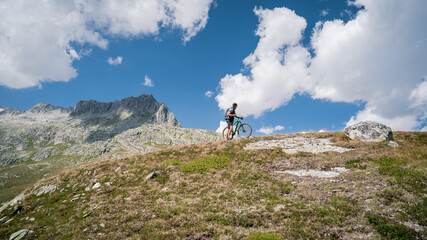 Wall Mural - Mountain bike cyclist in sport equipment and helmet riding on rugged trails. Young cyclist watching from the top of the mountain beautiful sunny day