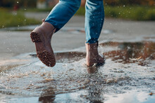 Woman Wearing Rain Rubber Boots Walking Running And Jumping Into Puddle With Water Splash And Drops In Autumn Rain.