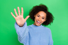 Photo Of Beaming Toothy Young Attractive Girl With Wavy Coiffure Dressed Blue Sweater Giving Five Isolated On Green Color Background