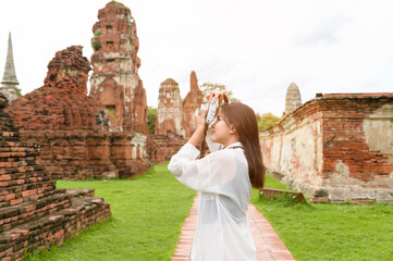 young beautiful woman traveling and taking photo at thai historical Park, Holidays and cultural tourism concept.