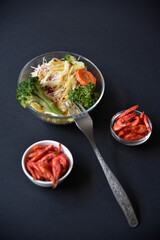 Wall Mural - Delicious salad in a glass salad bowl and red shrimp on a black background. Delicious breakfast of salad and shrimp.