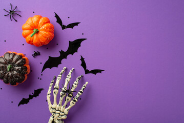 Wall Mural - Halloween creepy decorations concept. Top view photo of skeleton hand pumpkins bat silhouettes spiders and confetti on isolated violet background