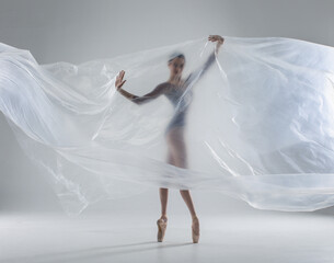 Wall Mural - Ballerina in dark ballet leotard dancing on ballet pointe shoes in white studio 