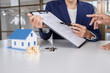 © MIND AND I - House model with real estate agent and customer discussing for contract to buy house, insurance or loan real estate background.