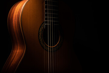 Classical guitar close up, dramatically lit on a black background with copy space