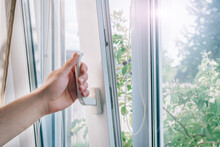 A Man's Hand Holds A Plastic Window Handle.Manual Opening White Plastic Pvc Window At Home.A Man Opens A Window, Closes A Plastic Frame In His Apartment.A Man Opens A Window With A Mosquito Net.
